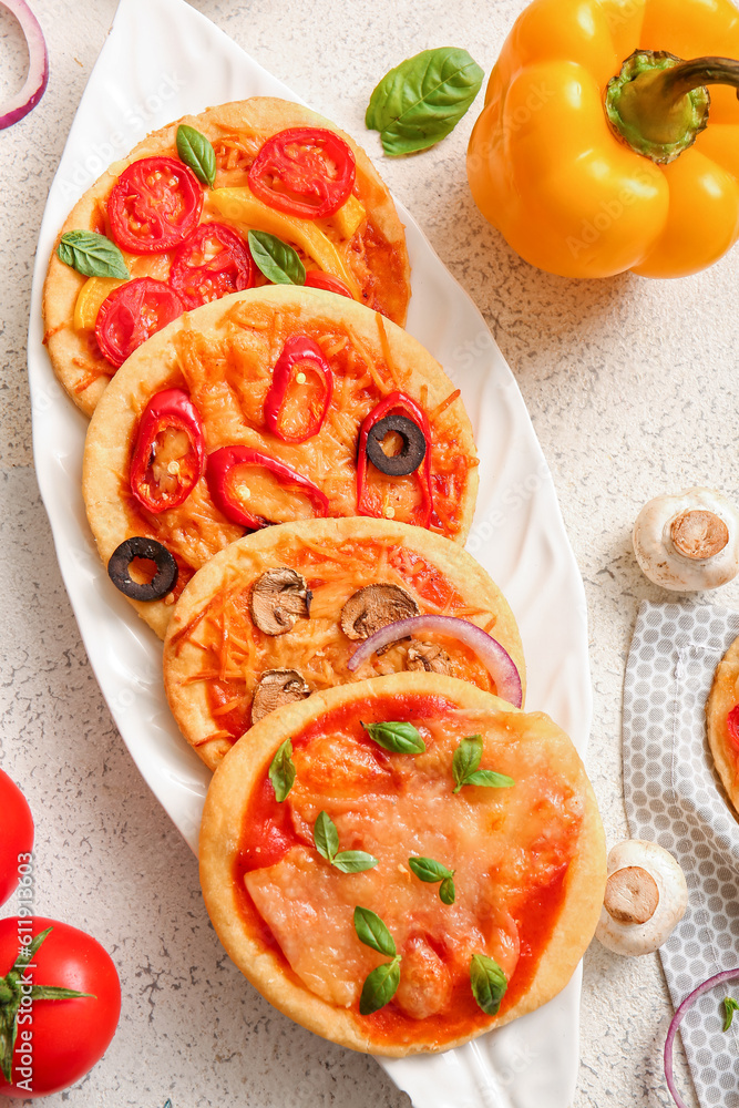 Plate with different tasty mini pizzas on white background