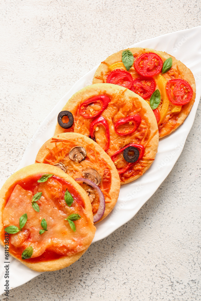 Plate with different tasty mini pizzas on white background