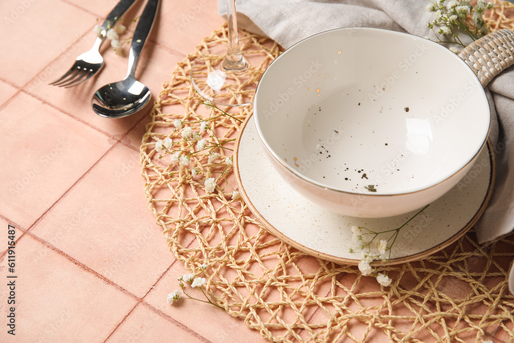 Wicker mat with stylish table setting on pink tile background