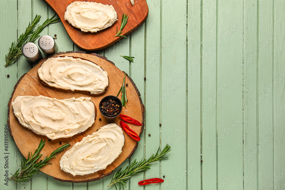 Board of tasty sandwiches with cream cheese on green wooden background