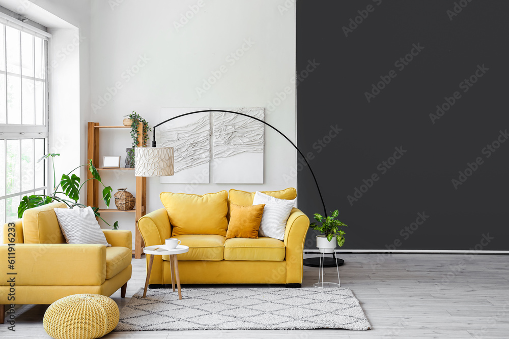 Interior of light living room with yellow sofa and armchair near big window