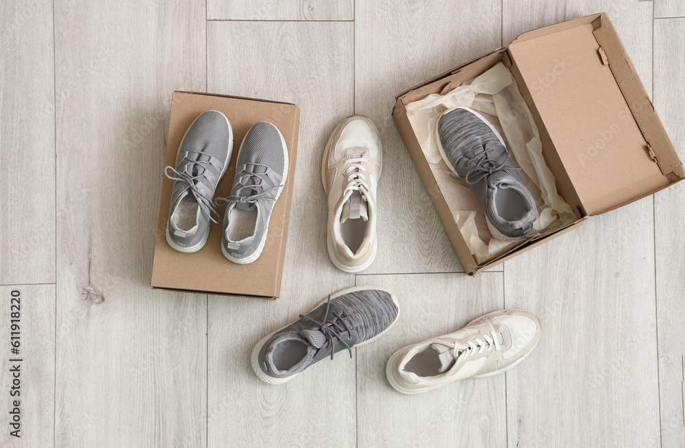 Cardboard boxes with different sneakers on light wooden background