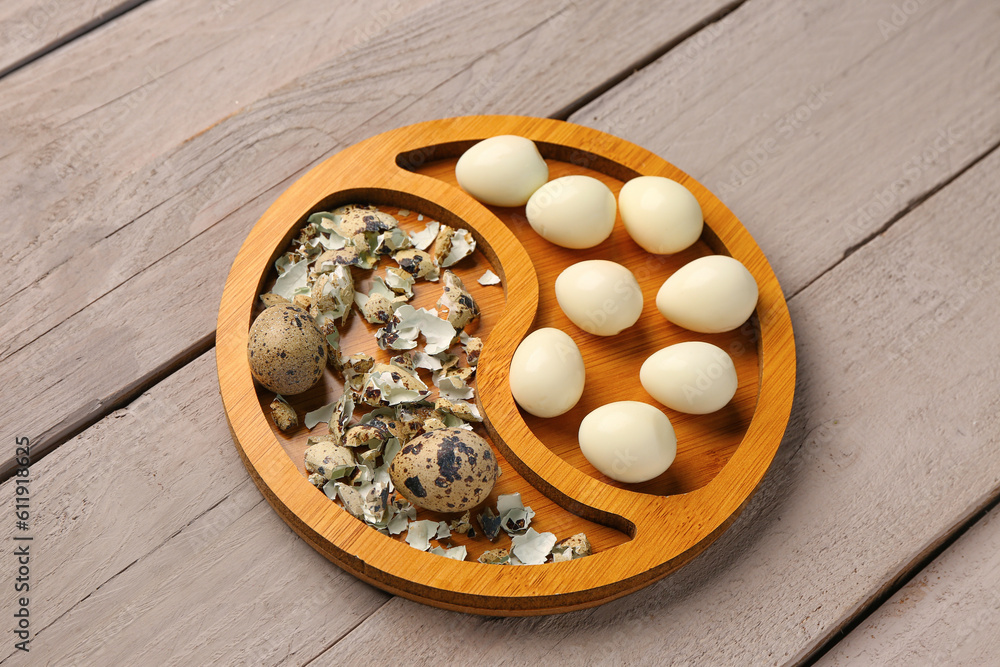 Board of boiled quail eggs with shells on grey wooden background