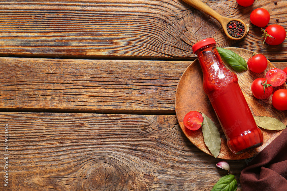 Plate with glass bottle of ketchup and tomatoes on wooden background