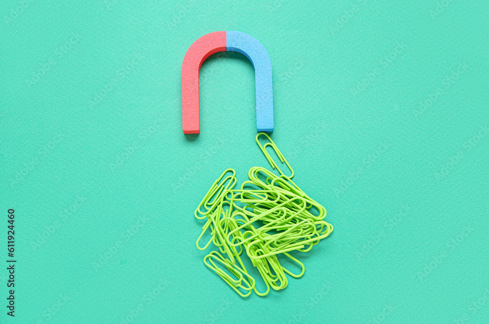 Magnet with heap of paper clips on green background