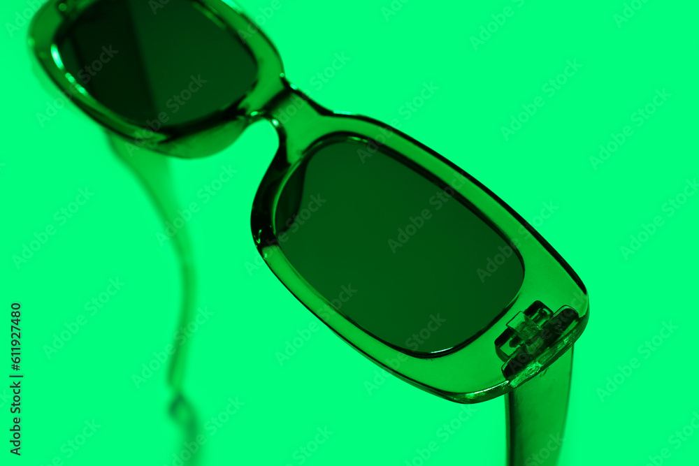 Stylish sunglasses on green background