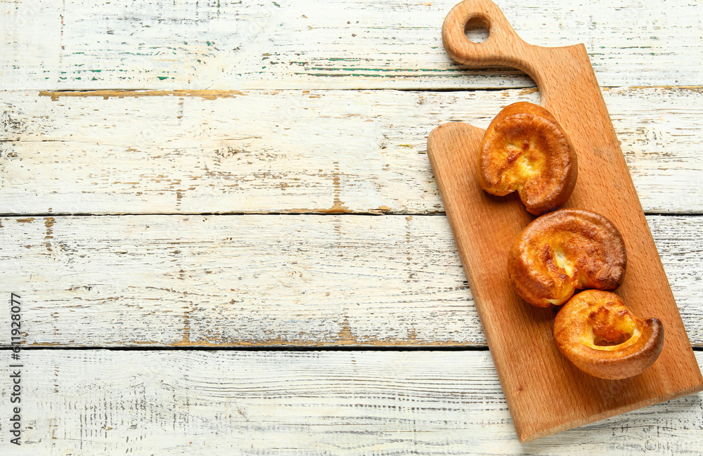 Board with tasty Yorkshire pudding on light wooden background