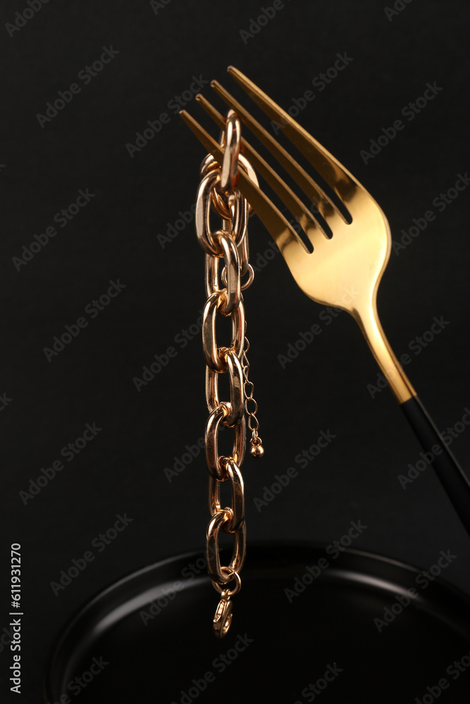 Fork with beautiful chain bracelet on black background