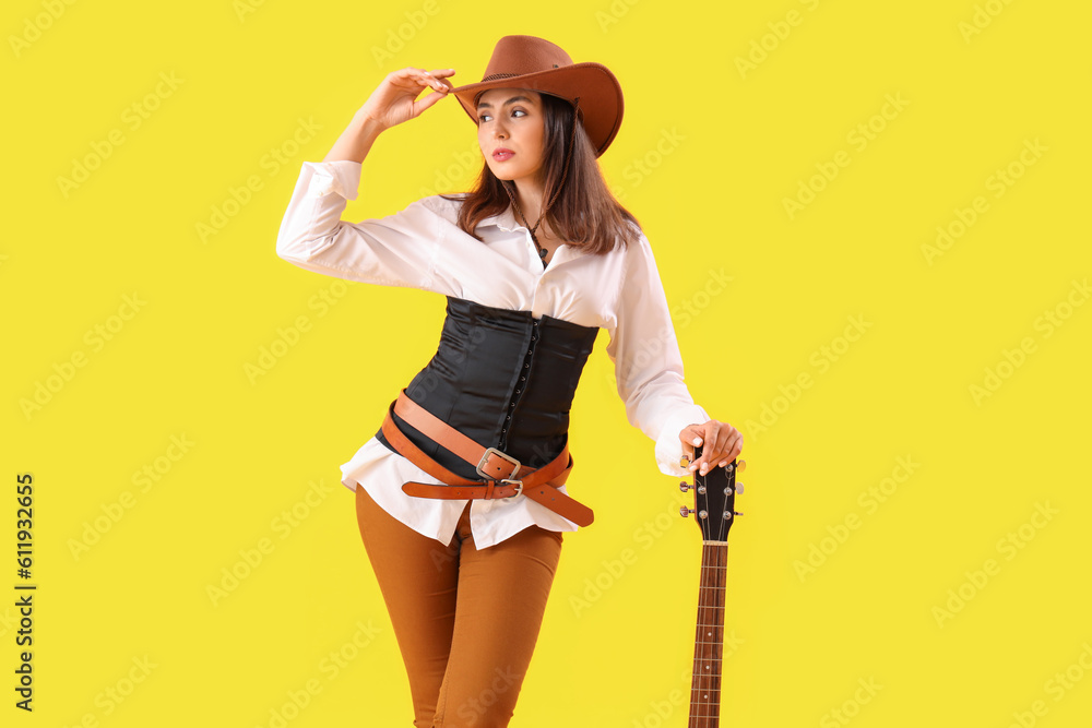 Beautiful cowgirl with guitar on yellow background