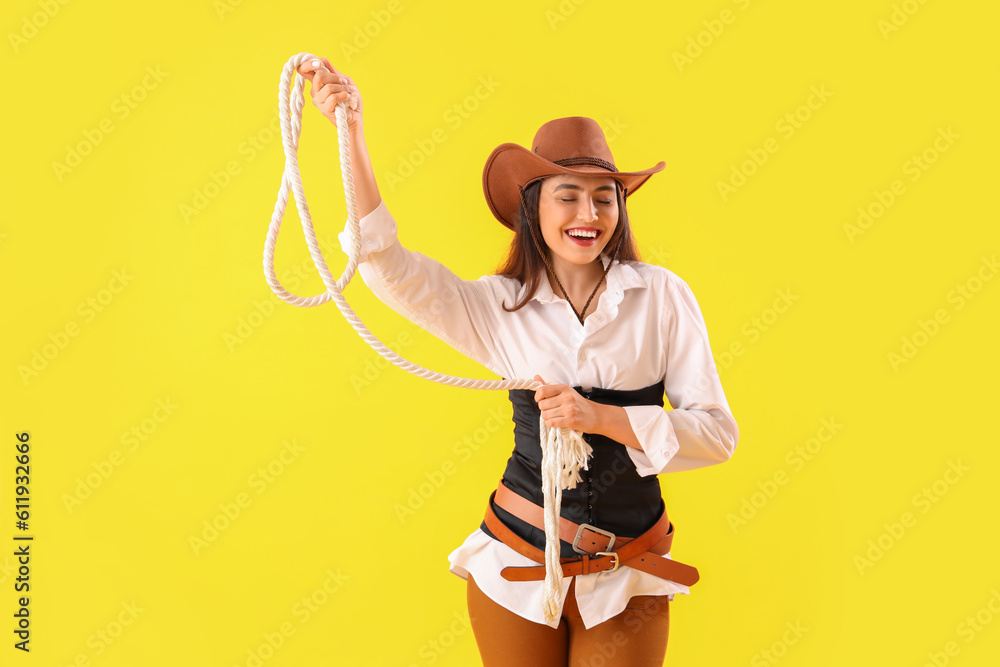 Beautiful cowgirl with lasso on yellow background