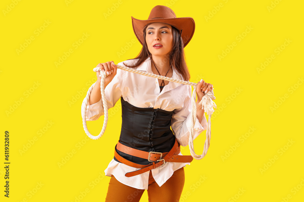 Beautiful cowgirl with lasso on yellow background