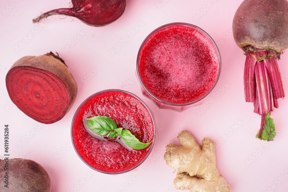 Glasses of healthy beet juice with basil and ginger on pink background