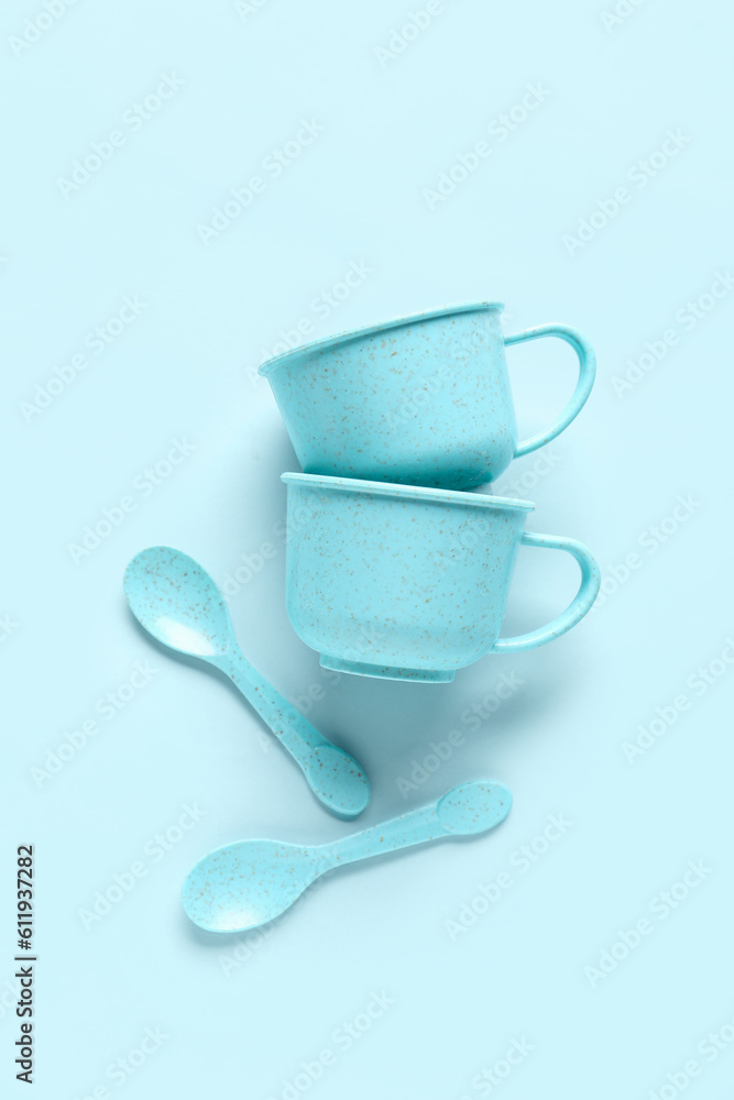 Cups with spoons for baby on blue background