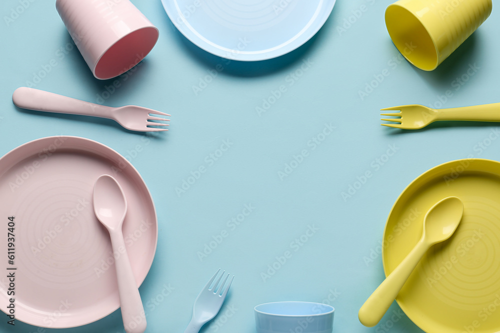 Frame made of different eating utensils for baby on blue background