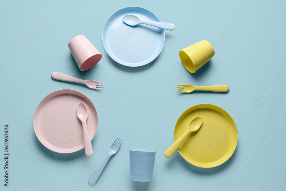 Frame made of different eating utensils for baby on blue background