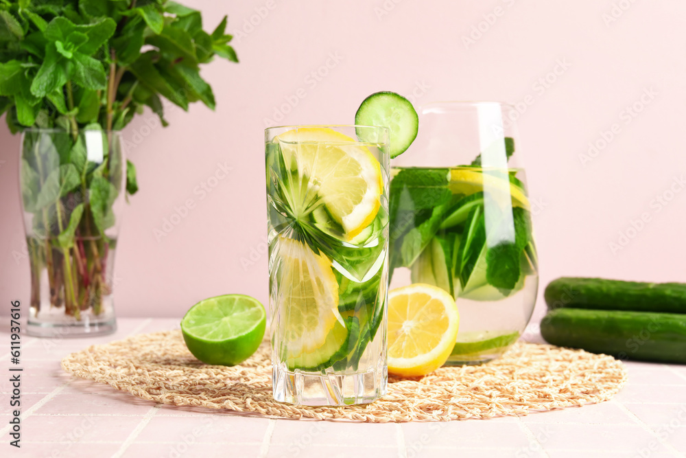 Glasses of infused water with cucumber slices on pink tile table