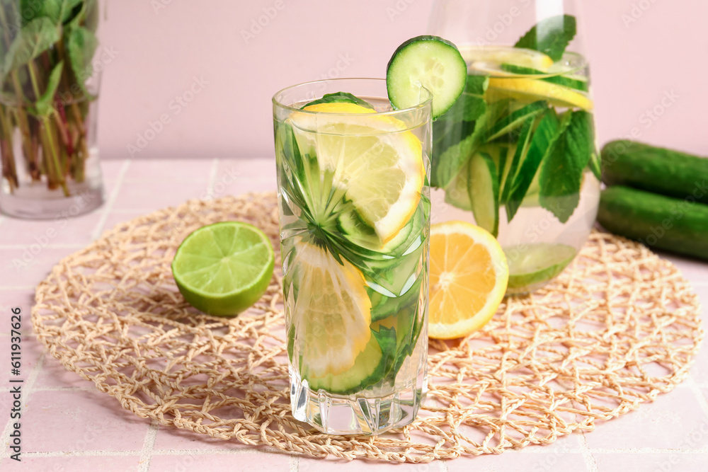 Glasses of infused water with cucumber slices on pink tile table