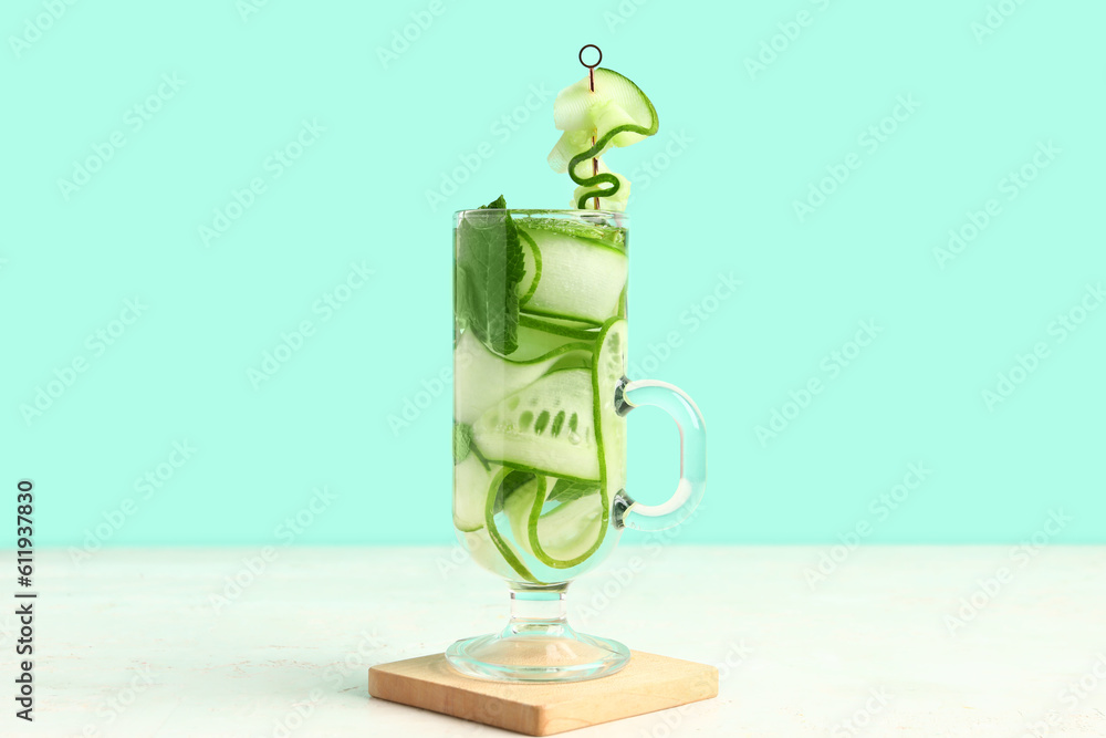 Glass of infused water with cucumber slices on white table