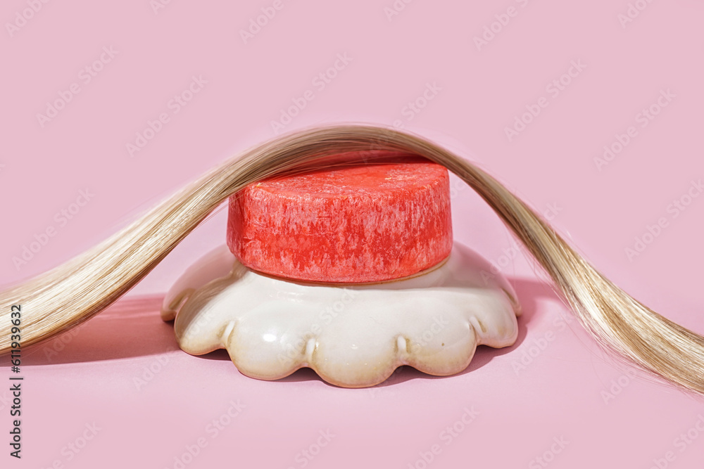 Red solid shampoo bar with hair on pink background