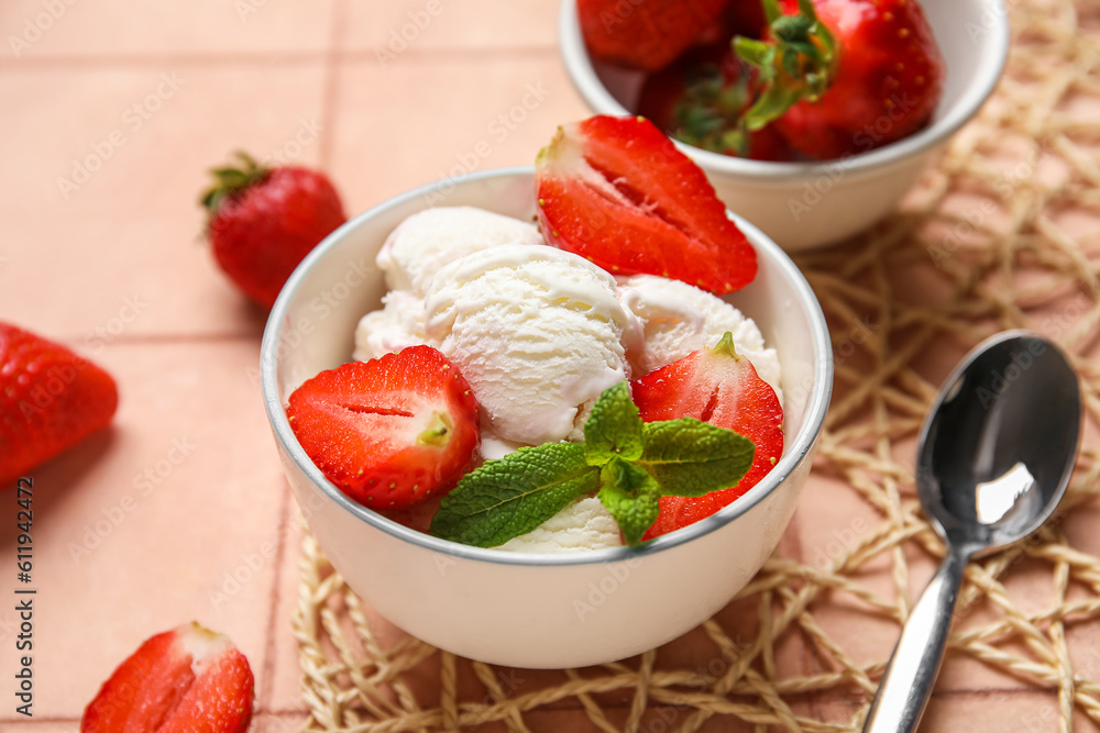 Bowl of vanilla ice cream with strawberries, mint and spoon on beige tile table