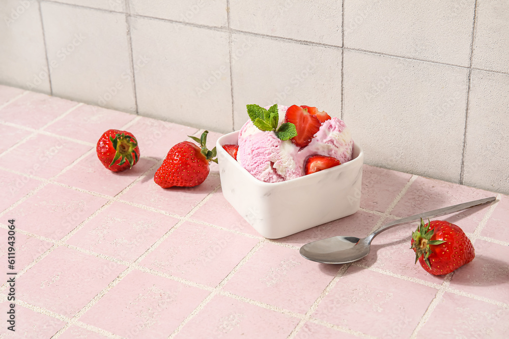 Square bowl of strawberry ice cream with mint, berries and spoon on pink tile table near white wall