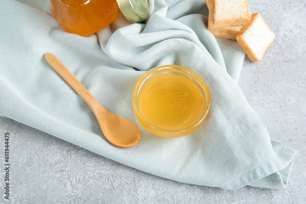 Bowl of acacia honey and crackers on light background, closeup