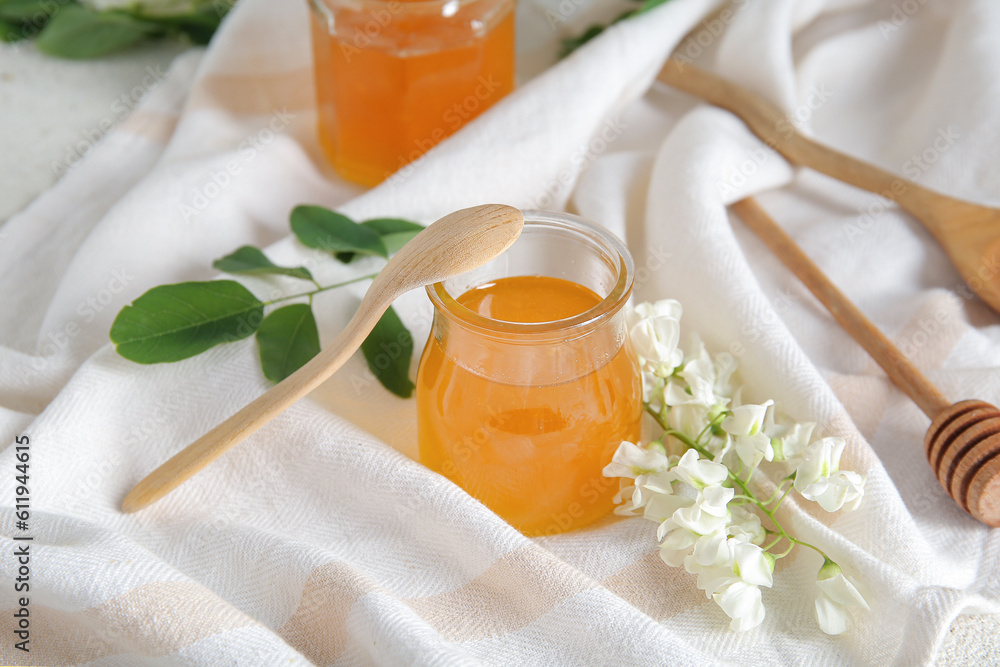 Jar of honey with flowers of acacia on table