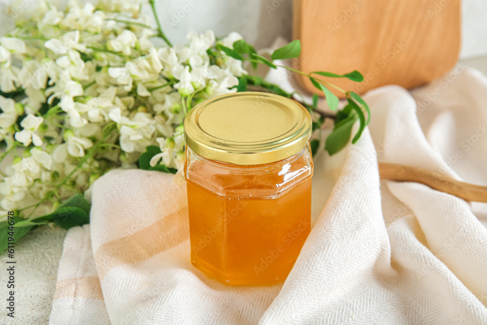 Jar of honey with flowers of acacia on table, closeup