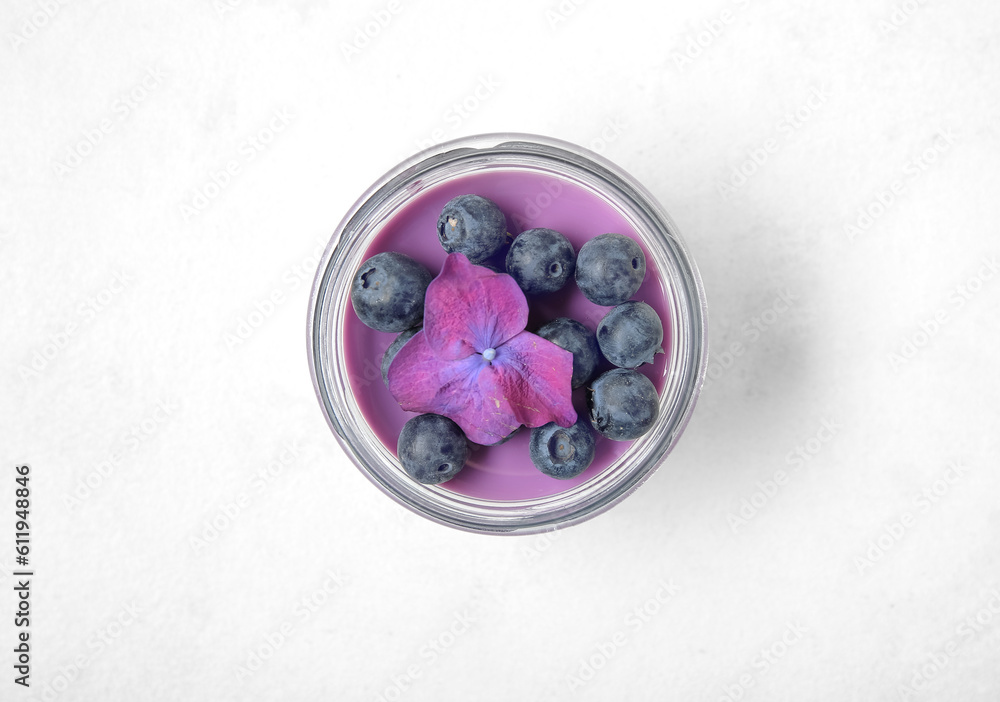 Glass jar of panna cotta with blueberry and beautiful hydrangea flower on white background