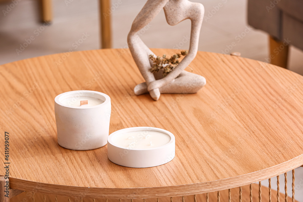 Holders with candles and decor on table in room, closeup