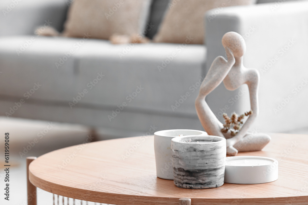 Holders with candles and decor on table in room, closeup