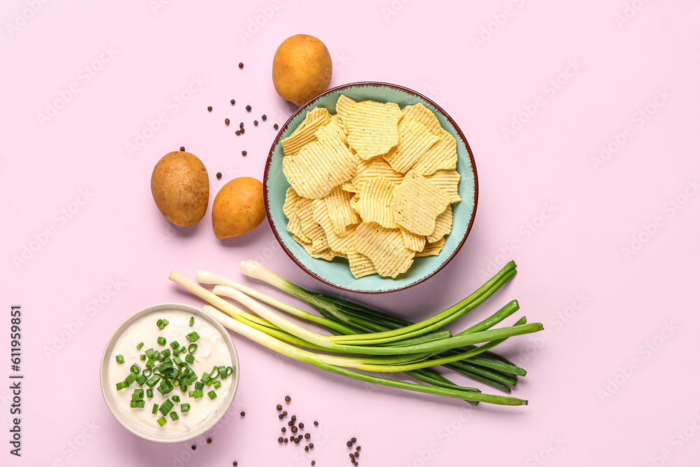 Bowl of tasty sour cream with sliced green onion and potato chips on lilac background