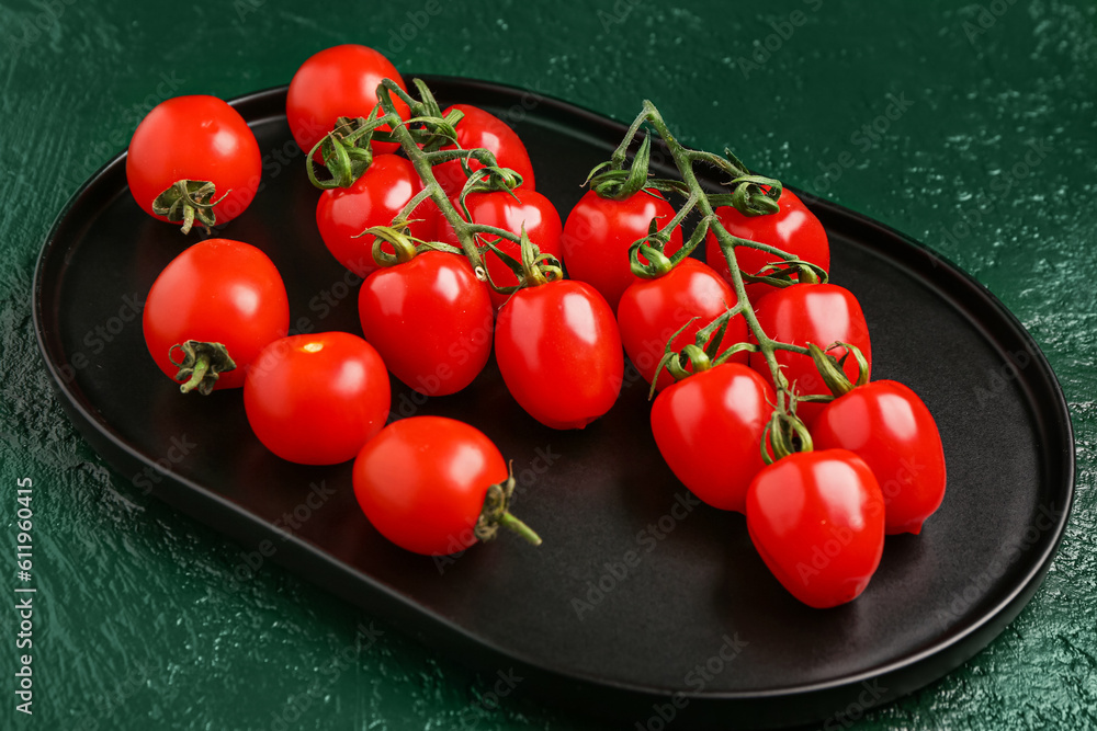 Tray with fresh cherry tomatoes on green background