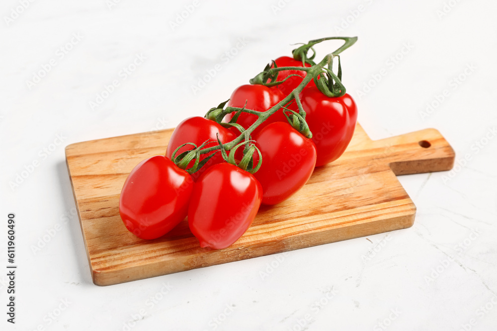 Wooden board with fresh cherry tomatoes on white background