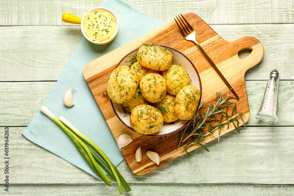 Plate of boiled baby potatoes with dill and scallion on green wooden background