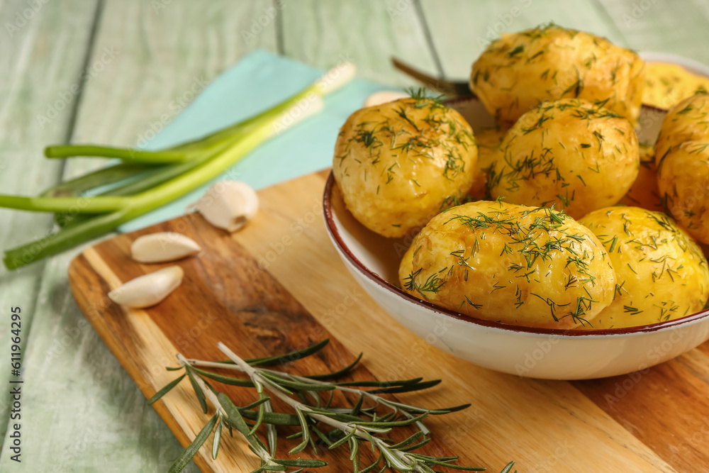 Plate of boiled baby potatoes with dill and scallion on green wooden background