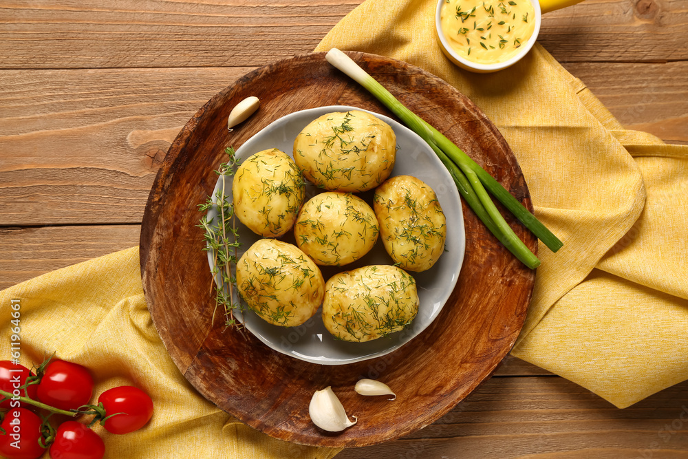 Plate of boiled baby potatoes with dill and green onion on wooden background