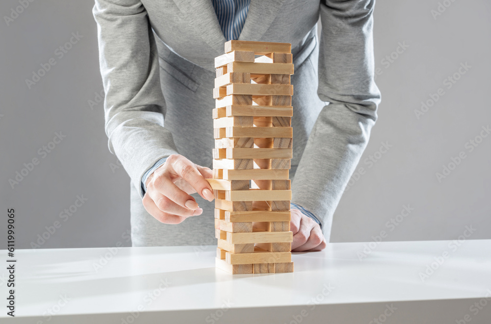 Businesswoman removing wooden block from tower