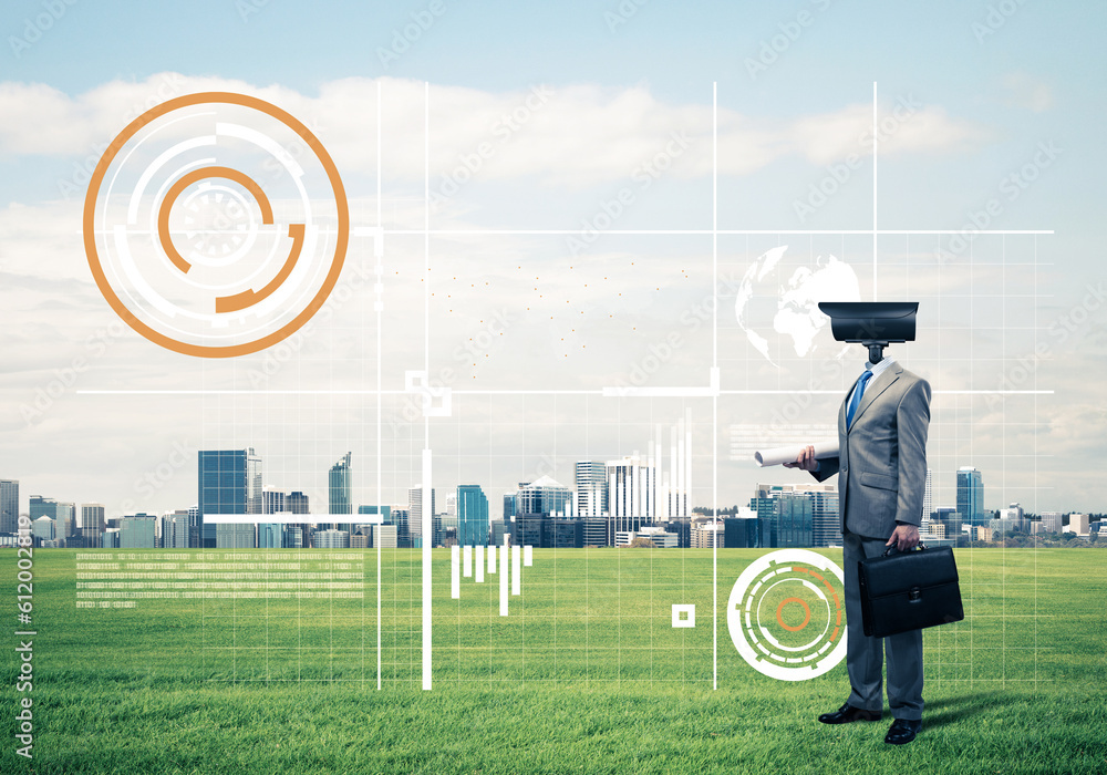 Camera headed man standing on green grass against modern cityscape