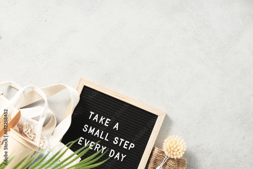 Take a small step every day letter board and zero waste no plastic accessories on grey stone backgro