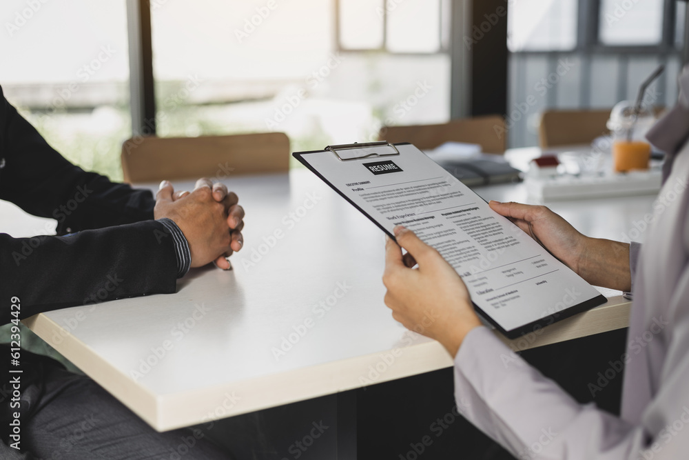 Woman submits an application to the personnel committee. The manager reads the resume and discusses 