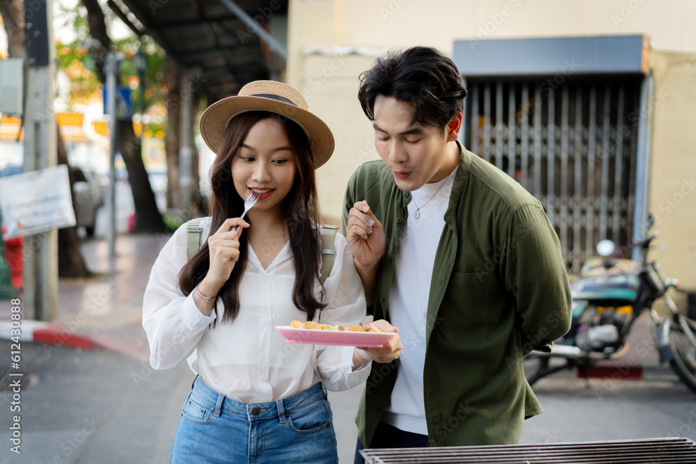  Asian couple traveler wearing a casual wear and hat in relationship buying a dessert snack on stree