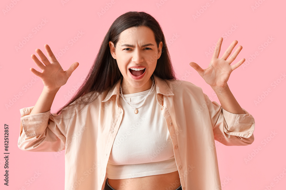 Angry young woman in shirt on pink background