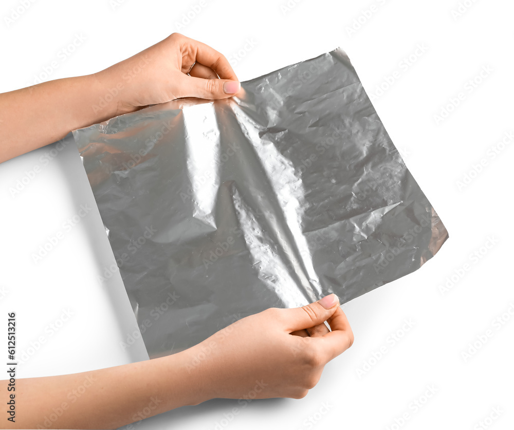 Female hands with sheet of aluminium foil on white background, closeup