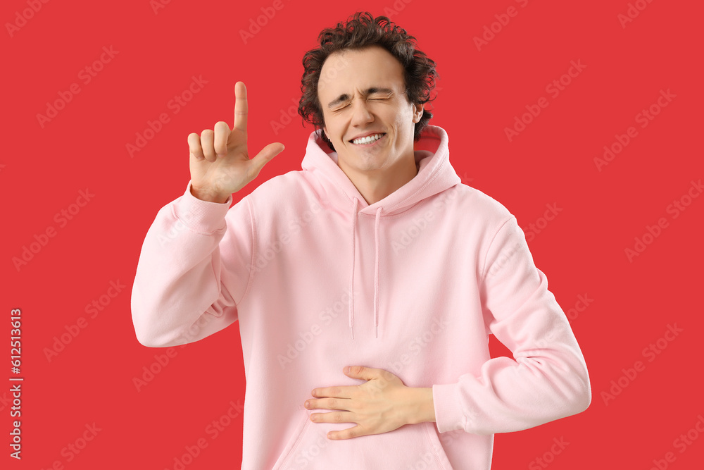 Young man showing loser gesture on red background