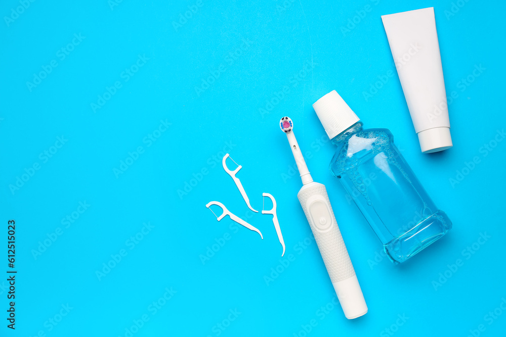 Floss toothpicks, electric brush, paste and rinse on blue background