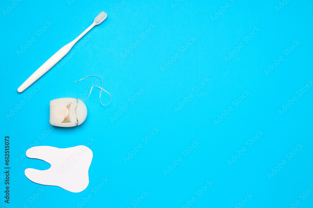 Dental floss, model of tooth and brush on blue background