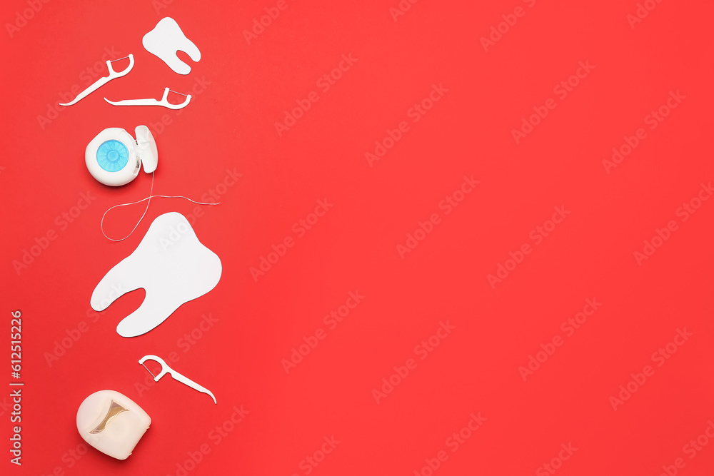 Dental flosses, toothpicks and tooth model on red background