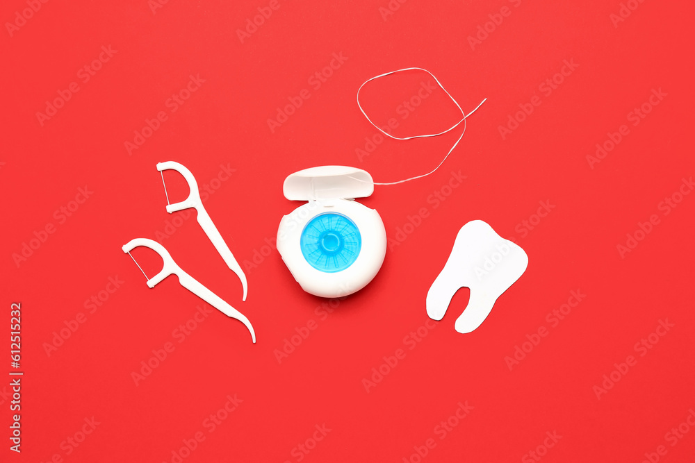 Dental floss, toothpicks and tooth model on red background