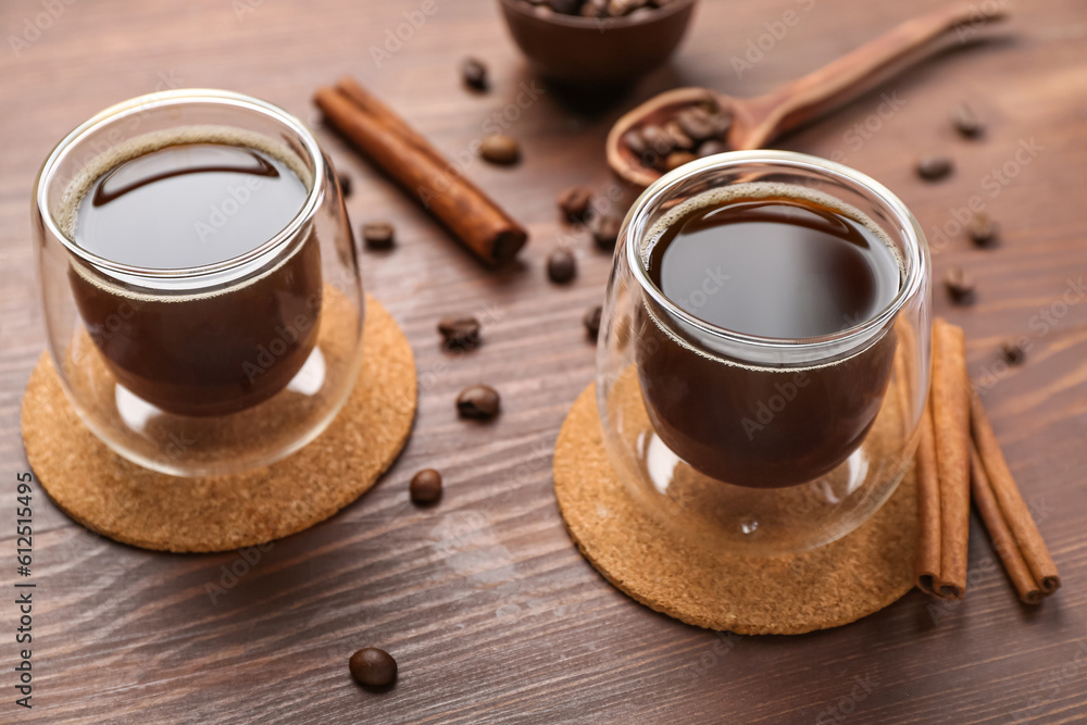 Drink coasters with glasses of coffee, cinnamon and beans on wooden table